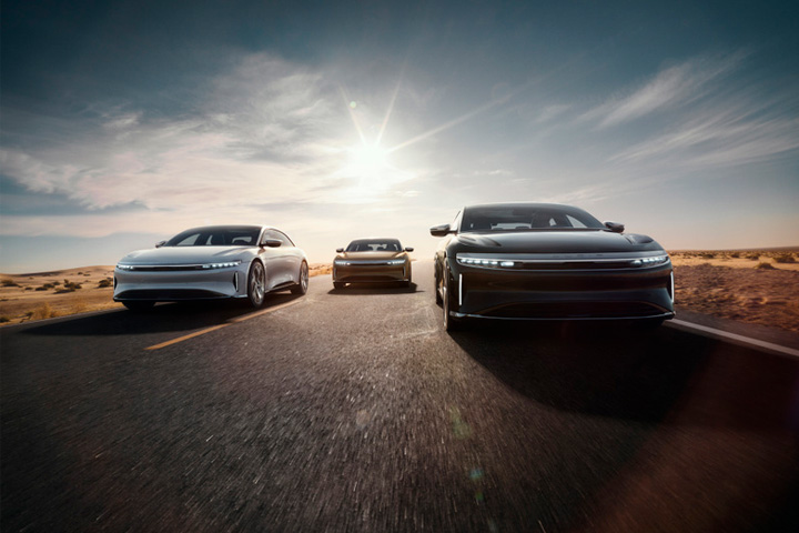 Carros elétricos da Lucid Air de cores diferentes em estrada no deserto com sol ao fundo