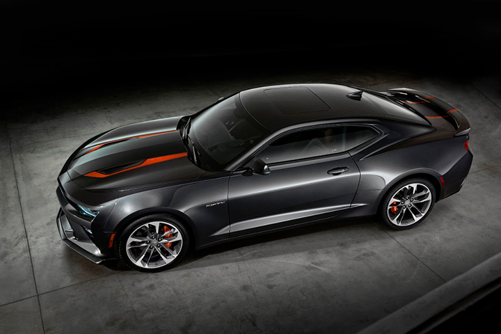 Chevrolet Camaro preto com detalhes laranja de edição especial de 50 anos em ambiente escuro com piso de cimento