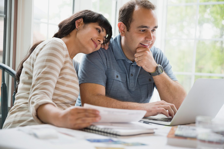 Casal relaxando em mesa de casa e acessando plataforma Carupi em seu notebook