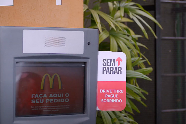 Detalhe de cabine de pedido em sistema drive-thru de lanchonete com selo de pagamento do Sem Parar