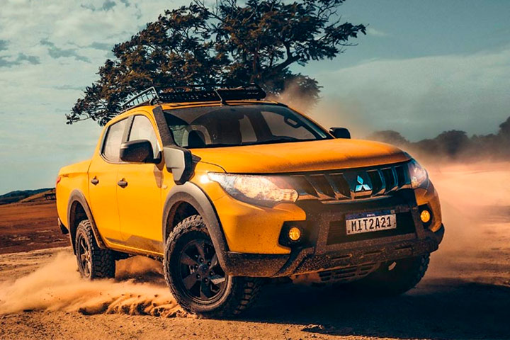 Picape L200 Triton Savana amarela derrapando e levantando poeira em cenário desértico