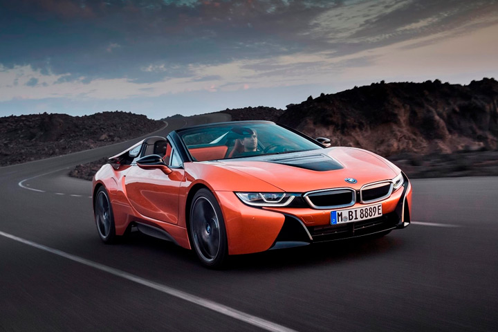 BMW i8 Roadster alaranjado em alta velocidade em rodovia ao anoitecer