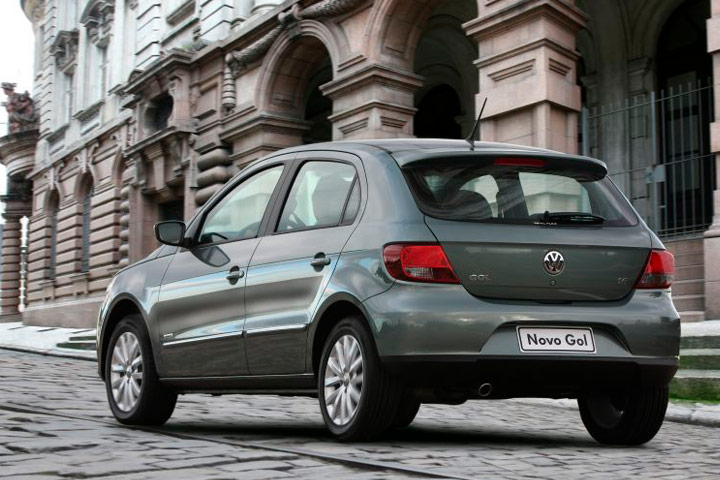 Gol G5 cinza em rua de paralelepípedos em frente a prédio de arquitetura antiga