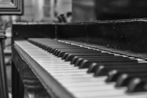 A close up black and white photo of upright piano.