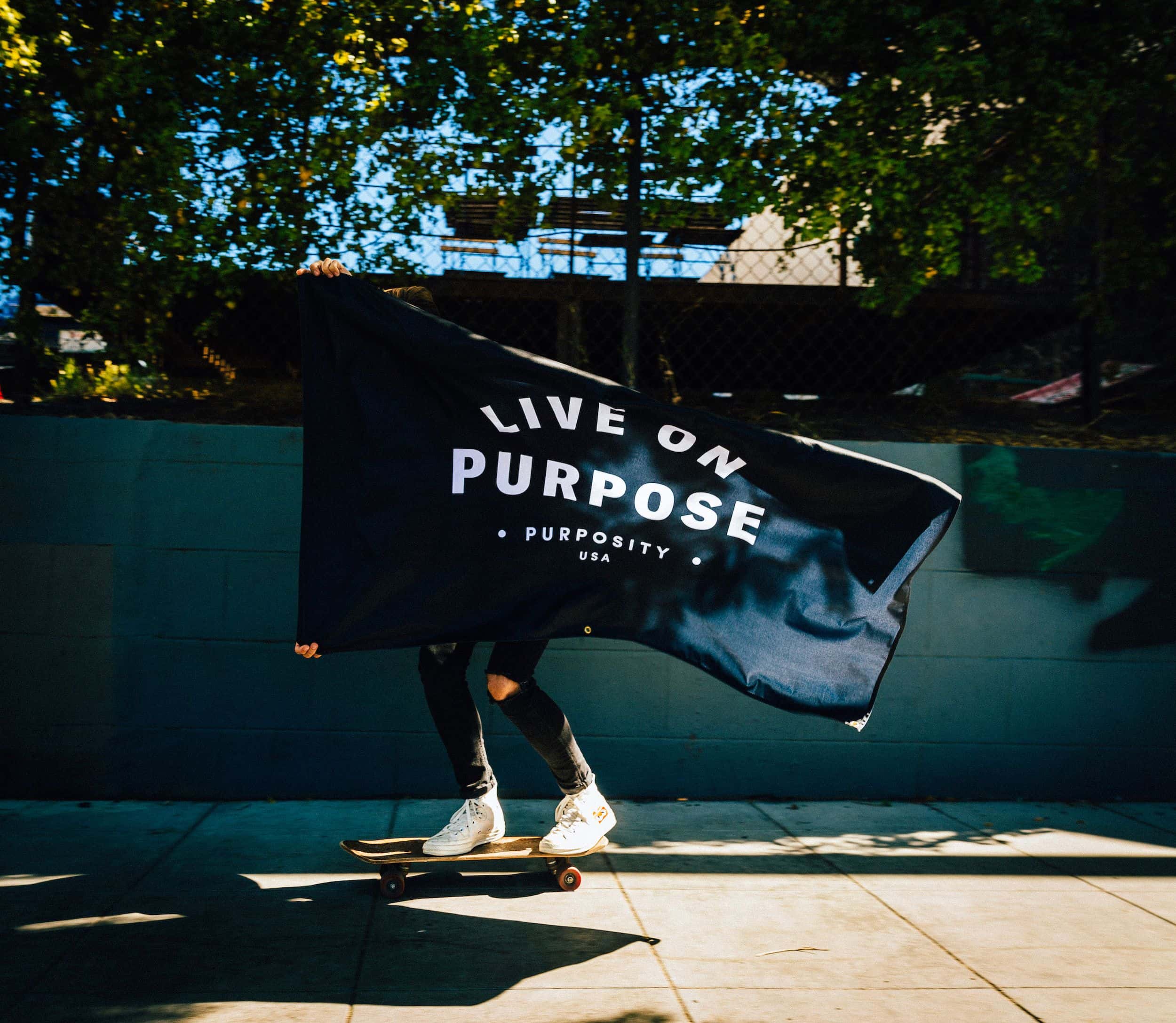 A woman holds a Purposity flag that reads "Live on Purpose"