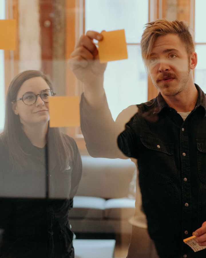 Kody Dahl and Katie Cooper, whiteboard employees, brainstorm in with post-its.