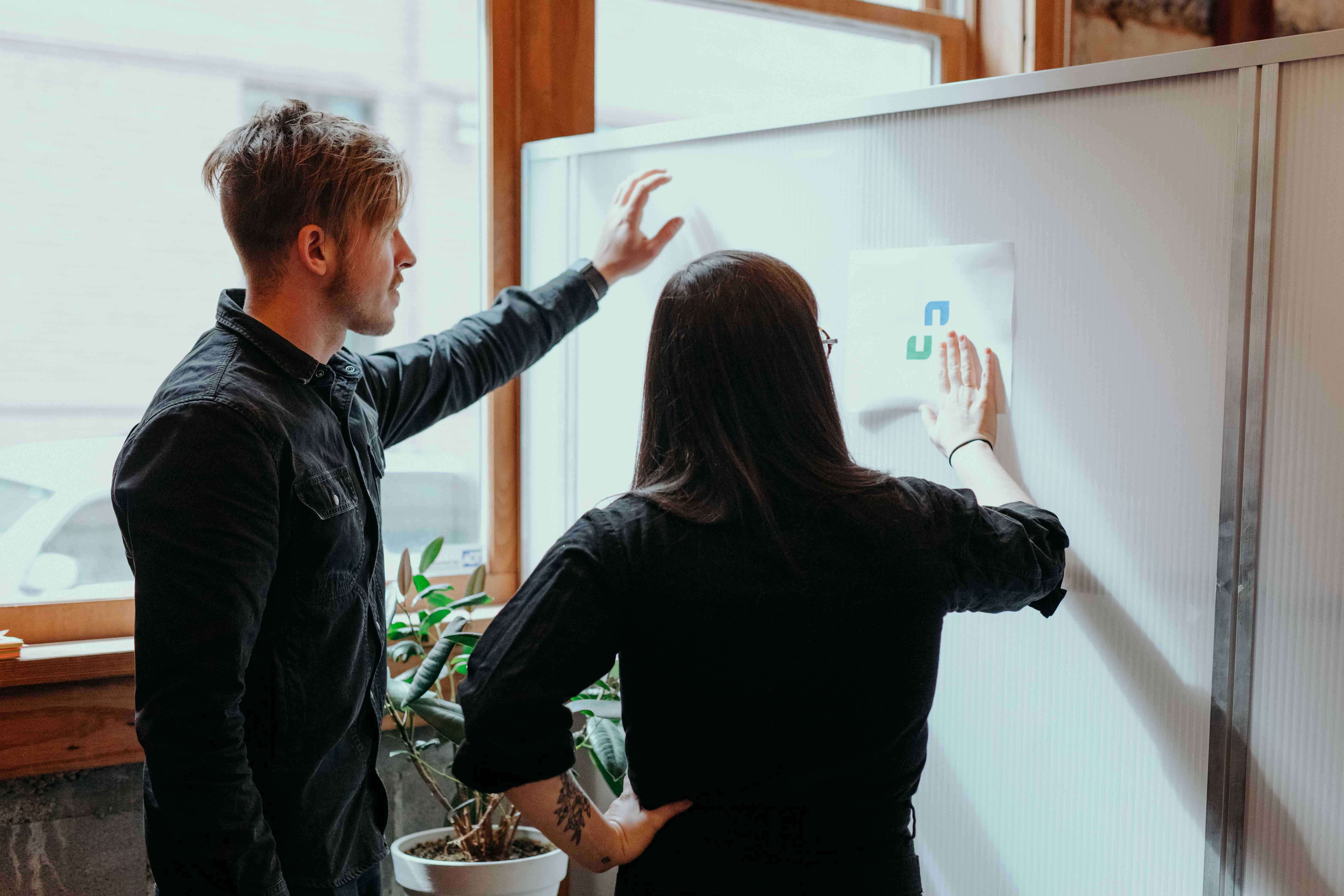 Kody Dahl and Katie Cooper, whiteboard employees, brainstorm in front of a whiteboard.