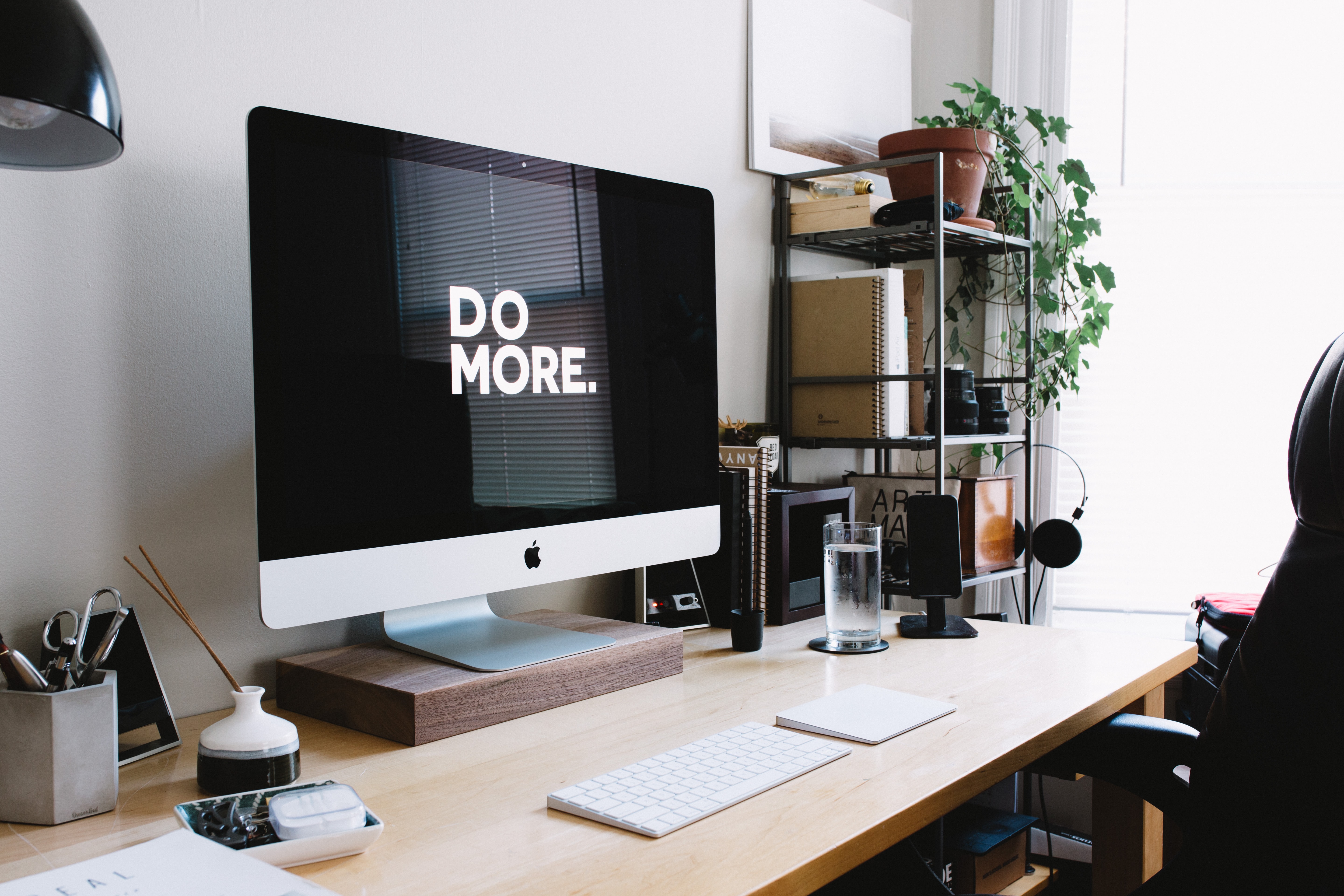Photo of Macbook on office desk with "Do More" screensaver.