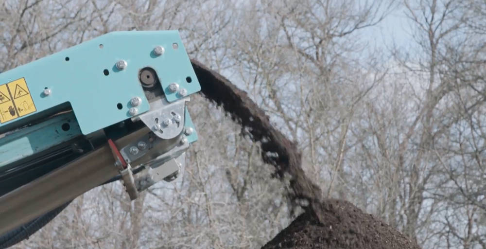 Topsoil being screening into a pile by a mobile scalping screen
