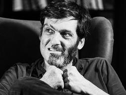 black and white image of dan ariely sitting in a recliner
