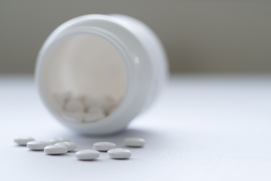 a pill bottle on its side with pills on the counter next to it