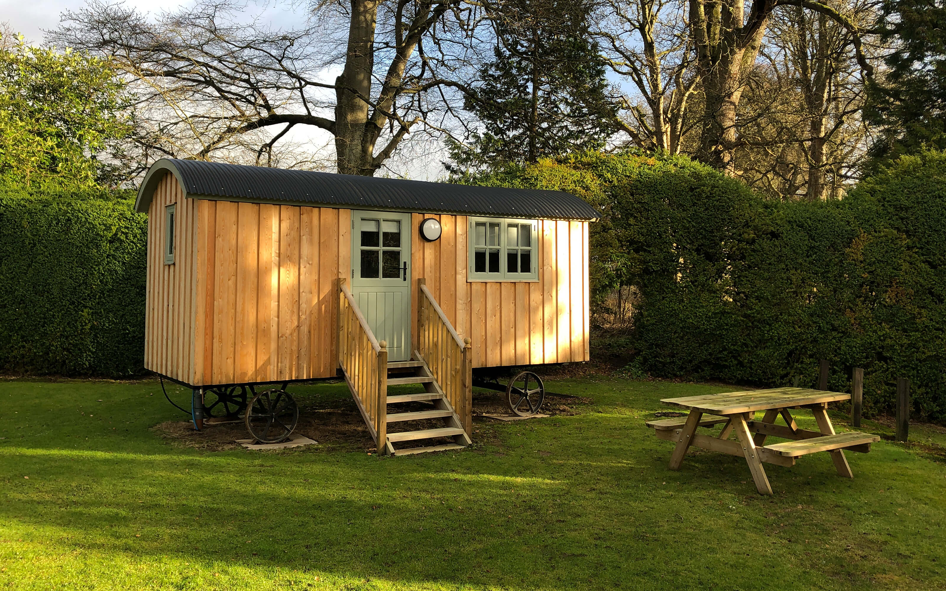 A secluded shepherds hut with a picnic table on the lawn.