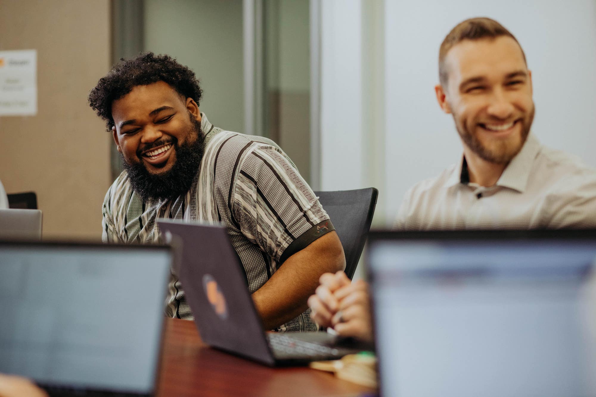Two Steam Logistics Employees laugh while seated at the conference table.