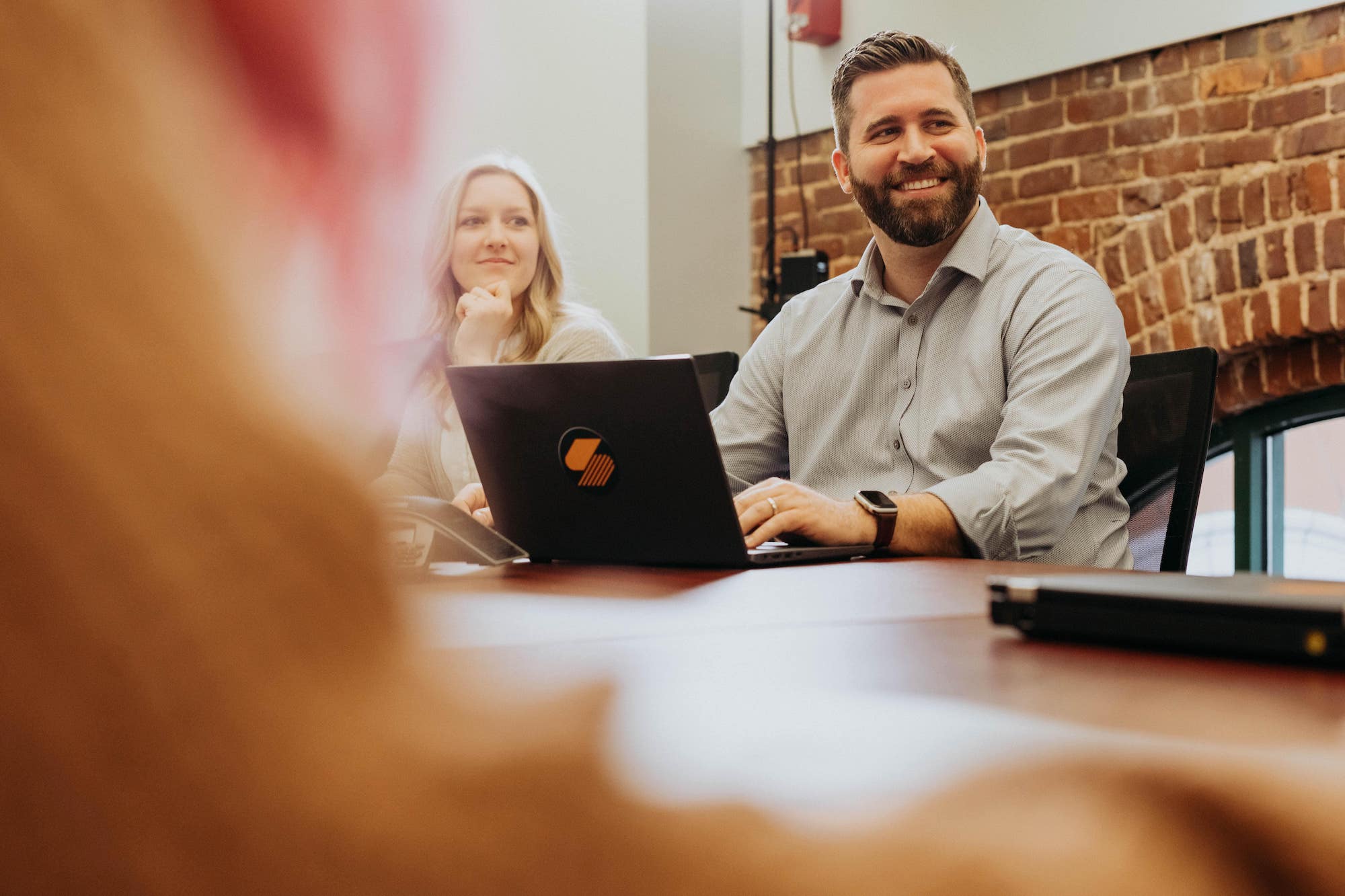 A Steam Logistics employee smiles while seated in the conference room, his laptop in front of him.