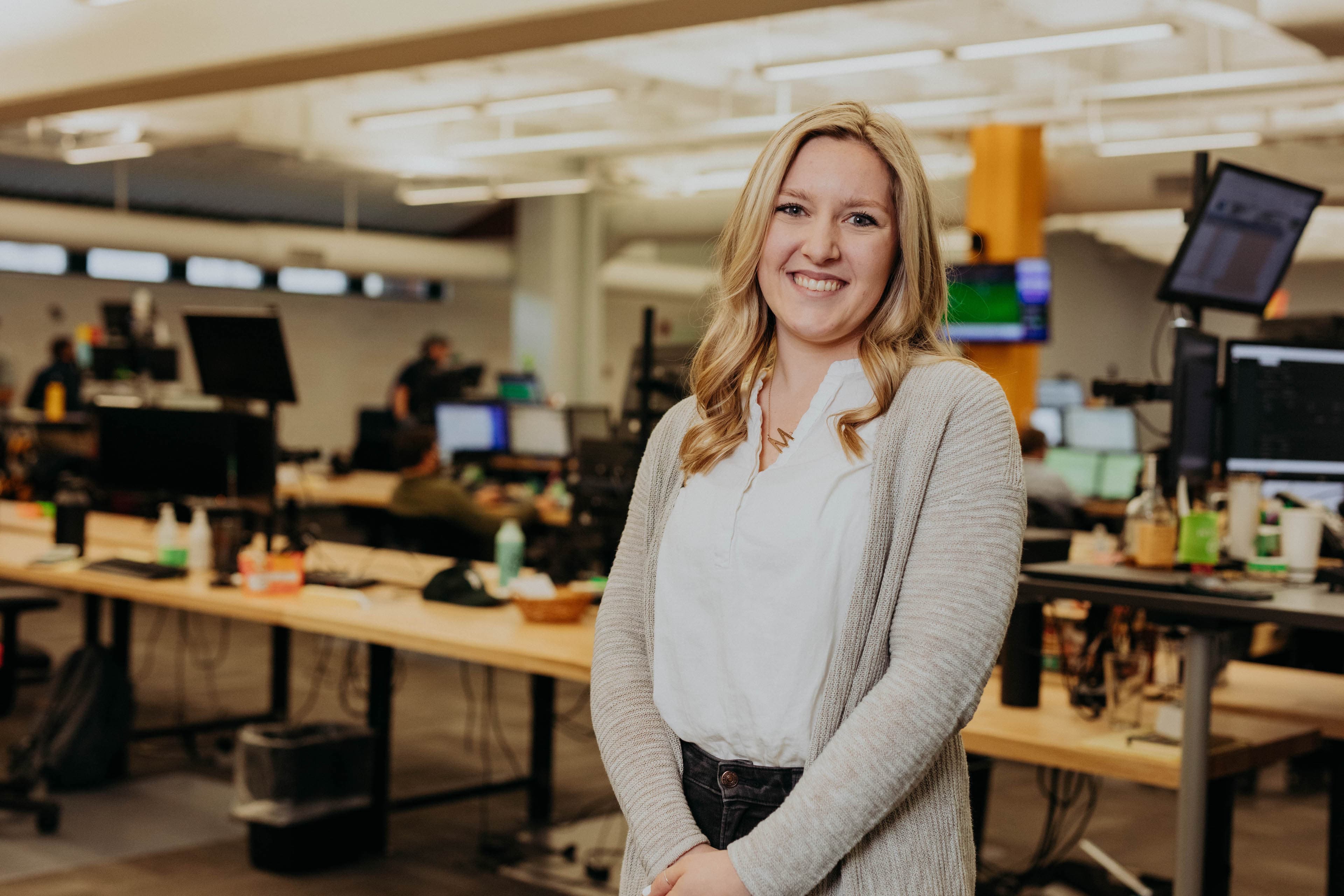 A Steam Logistics employee smiles while posing in front of the open area work station.