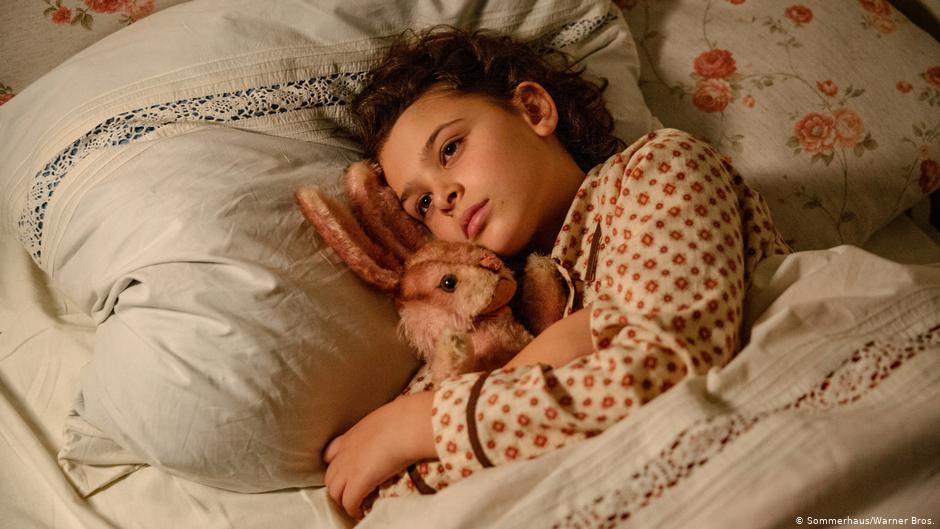 image of girl laying in bed holding rabbit, still from movie