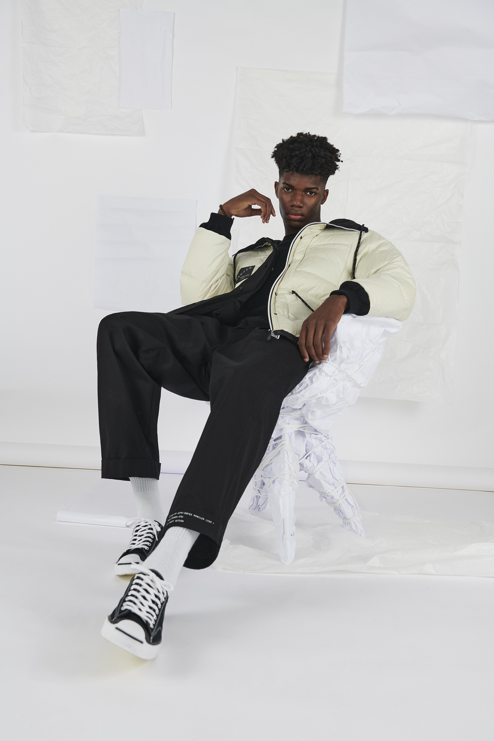 Model wears trainers, trousers, t-shirt and coat by 7 Moncler Frgmt Hiroshi Fujiwara