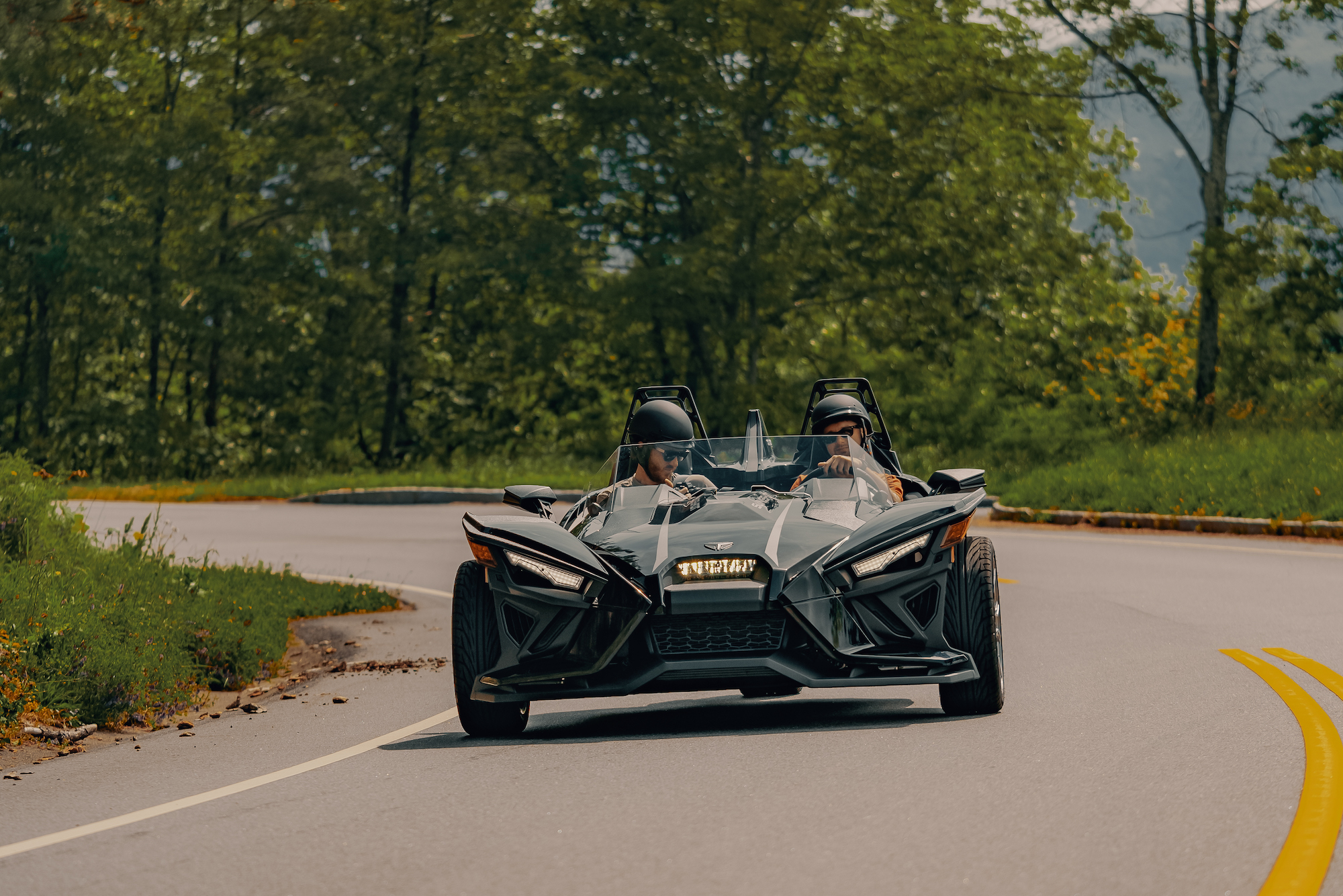 Polaris Slingshot driving down the road around a corner - Polaris Slingshots are available as rentals at the Mountain Mile Mall at Mountain Mile Adventures in Pigeon Forge, Tennessee