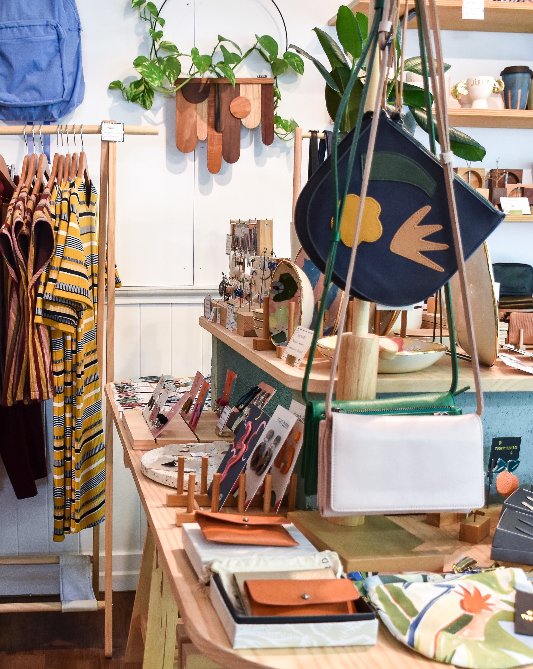 A photo of the interior of Square One Goods in Birmingham, AL. Lots of items are displayed like clothing, bags, clutches, and more.