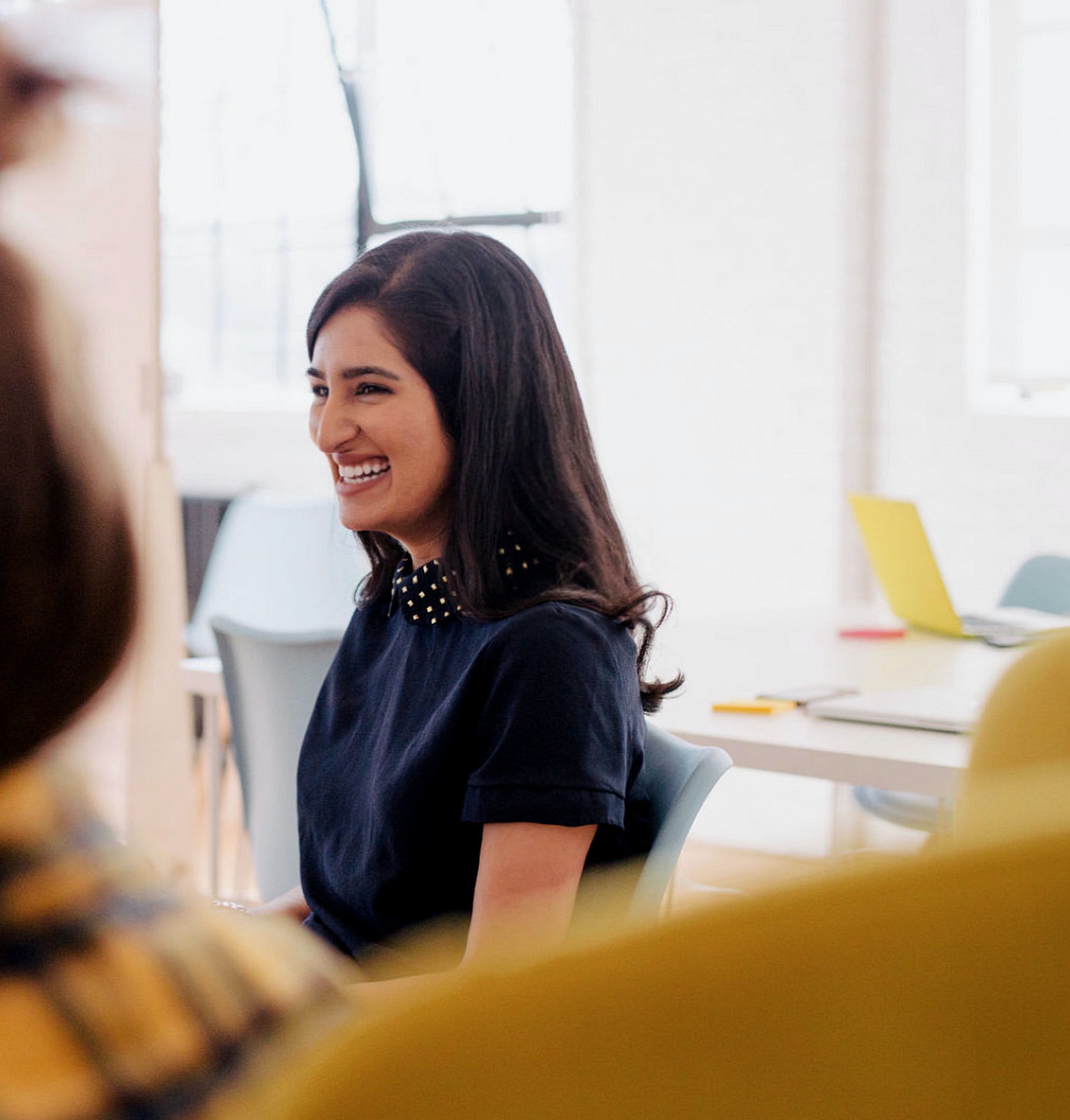 A woman smiles while listening to a presentation.