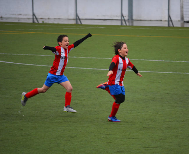 Junior soccer athletes celebrate on the pitch.