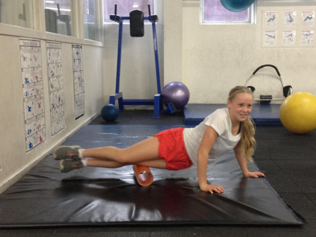 Sarah practicing her quad foam rolling in the gym.