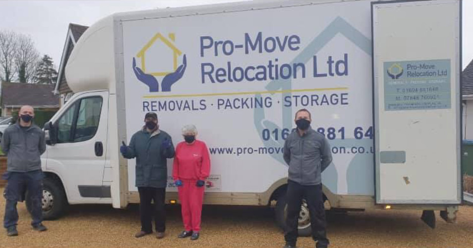 The Pro Move Team standing outside by a van with their COVID protection on