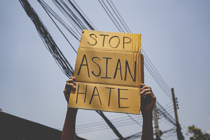A photo of a person holding a homemade sign which reads "Stop Asian Hate"