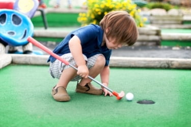 Kid playing mini golf