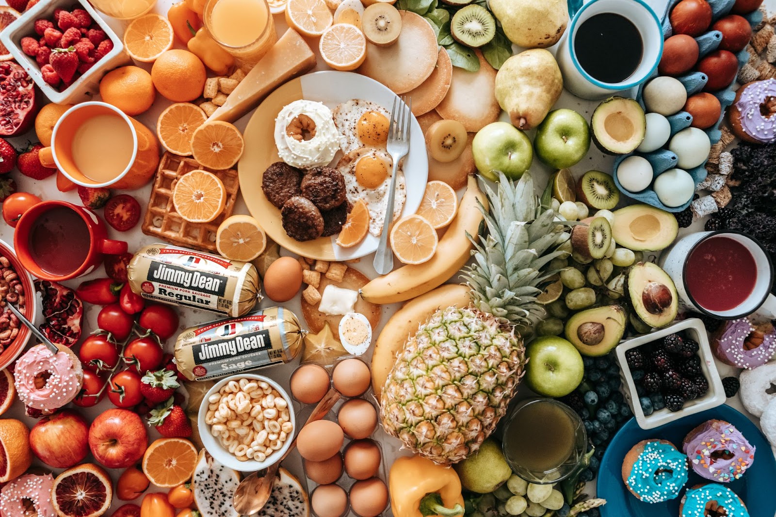Mesa farta e colorida com frutas, ovos, queijos e outros alimentos