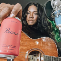 Image of a woman playing guitar with a Recess can