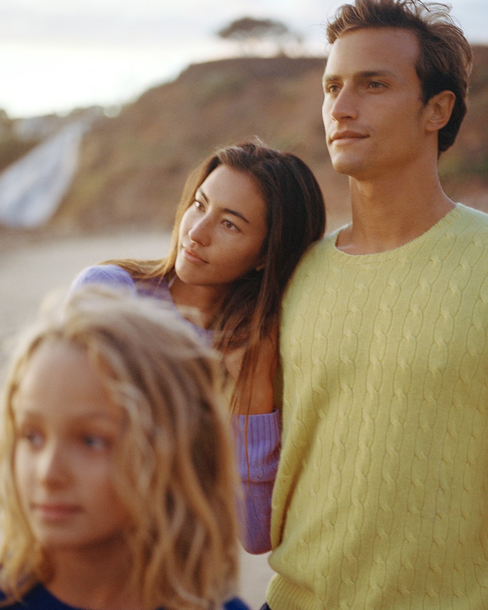 a family looking into the distance wearing polo ralph lauren sweaters at a rocky beachy terrain