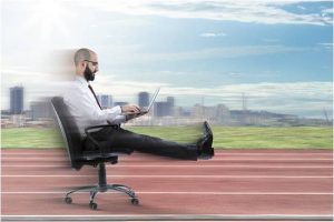 Man typing on a laptop from a speeding rolling chair on a running trac