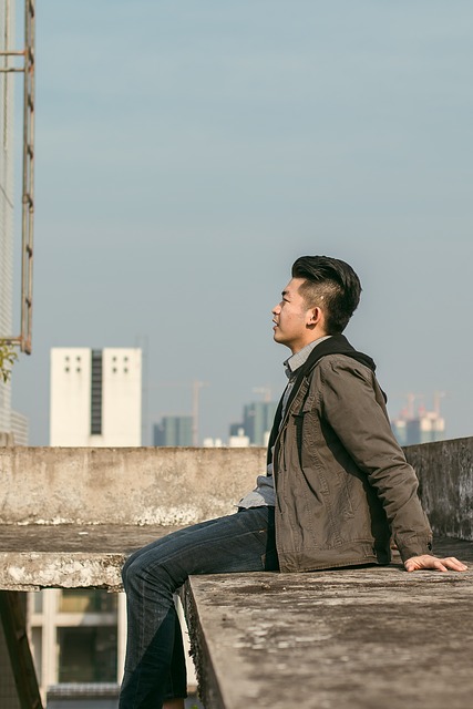 Man sitting on the edge of a building with a skyline behind him