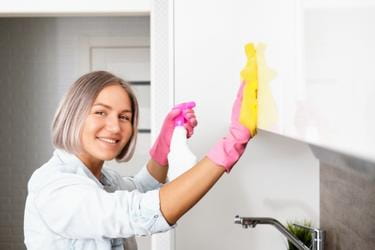 Woman cleaning the kitchen's cabinets