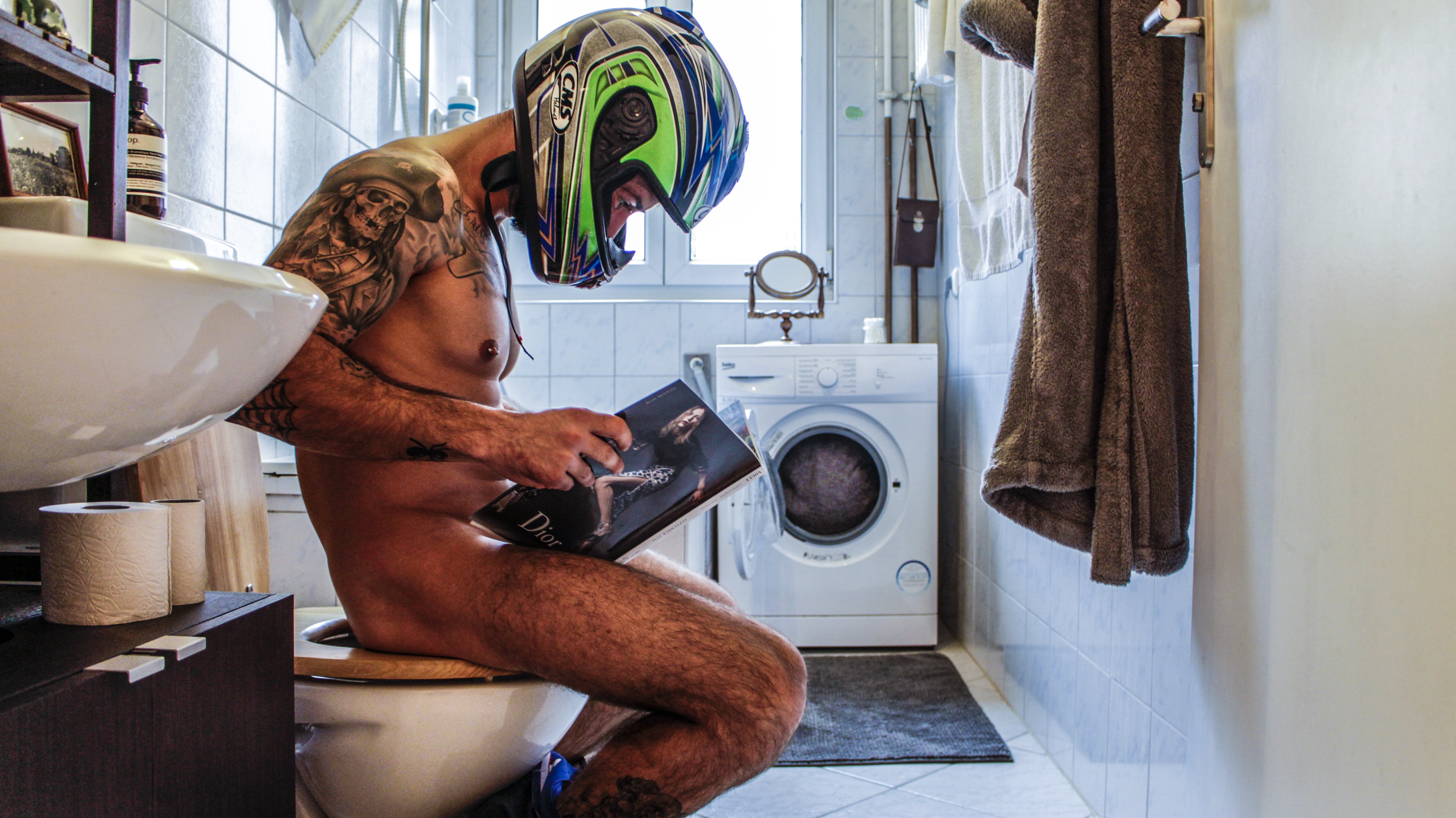 Man sitting on a toilet with the helmet on, photograph of Paco Pennino who won the Beazy Architecture contest
