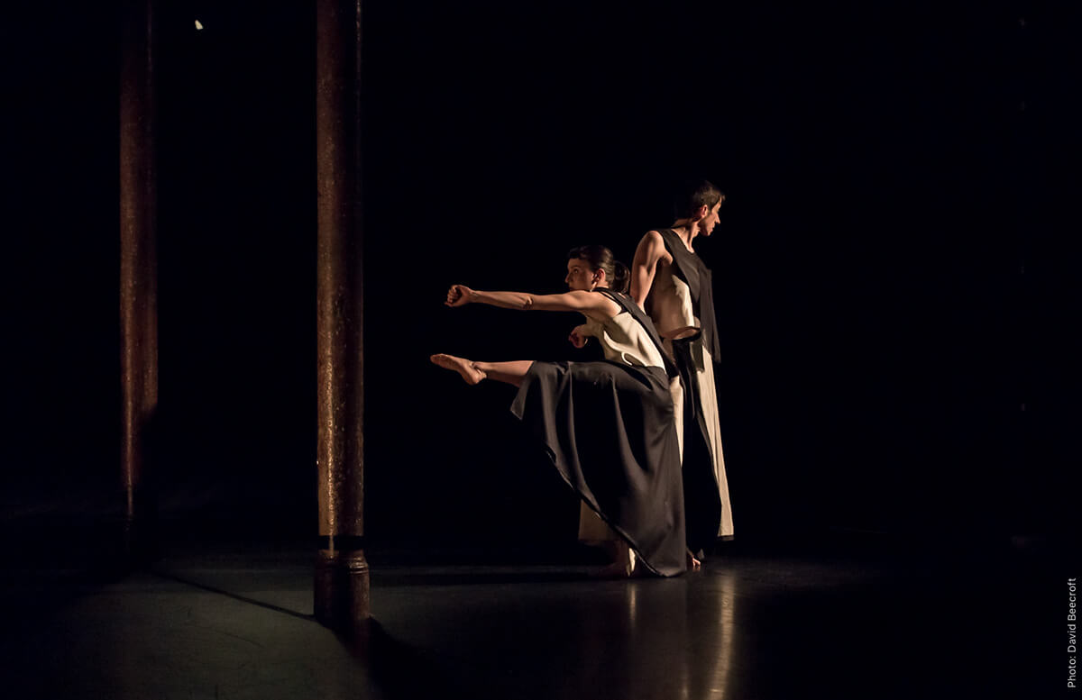 Two artists dressed in black and white performing on a dark stage.