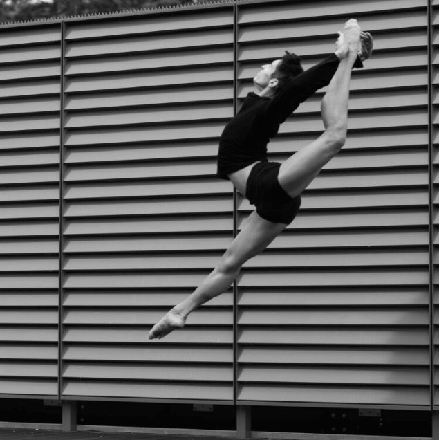 In black and white, a ballet dancer captured in the air.