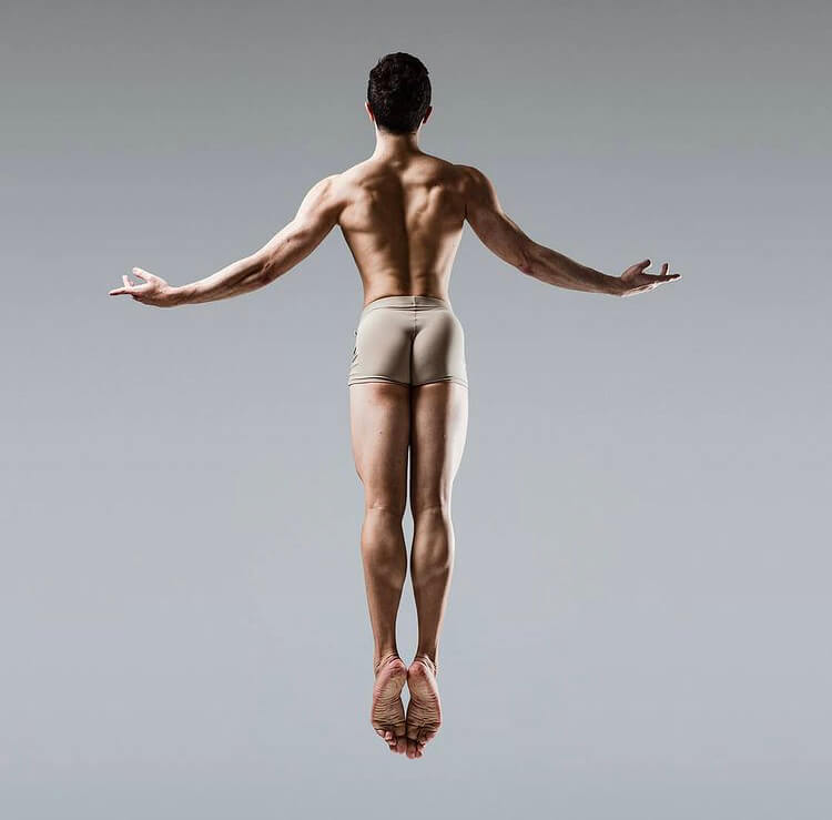 A male ballet dancer jumping backwards.