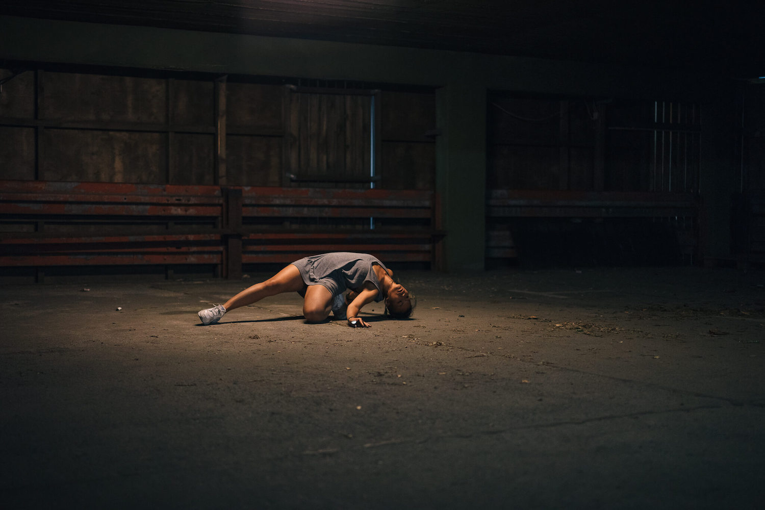 A girl dancing on the ground in the middle of a dark empty street.