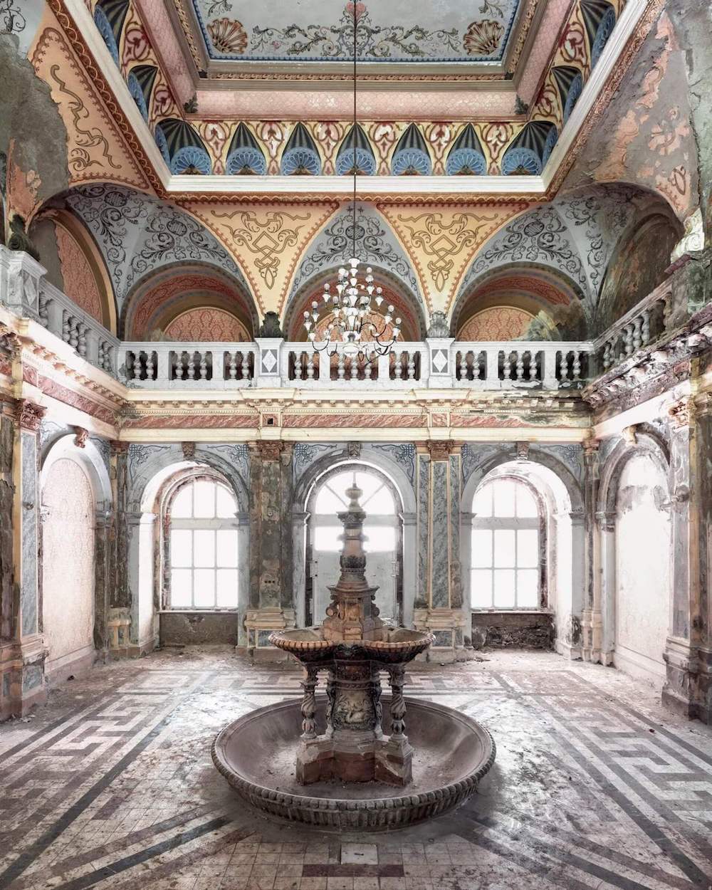 Interior of an old abandoned building with a fountain in the centre.