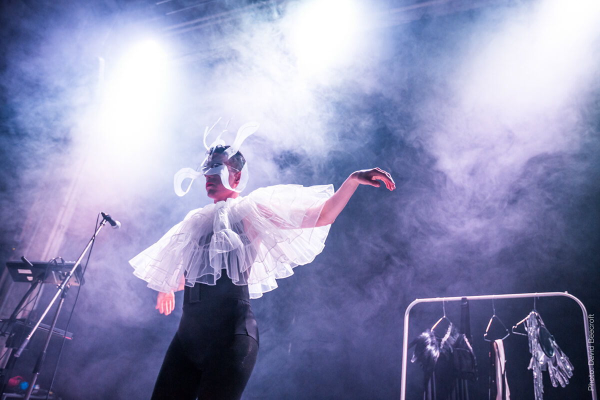 A singer with open arms on a smoky stage.