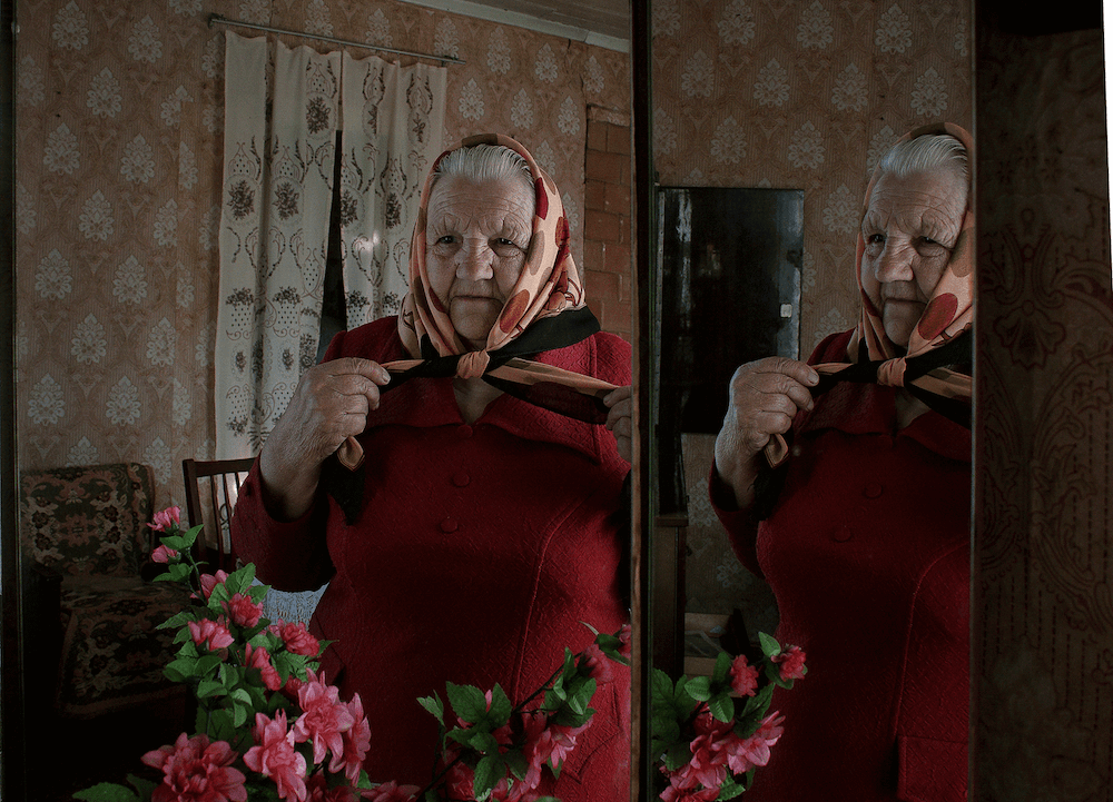 Portrait of grand mother with scarf in front of a mirror in Belarus by photographer Krystsina Shyla