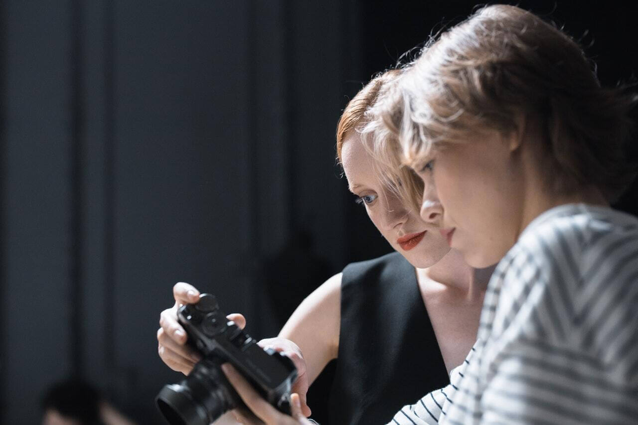 Two photographers looking at the screen of a camera.