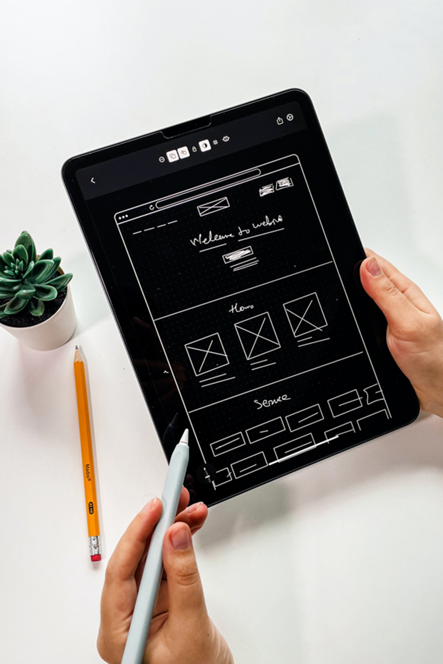 Person holding a tablet while creating a websites wireframe