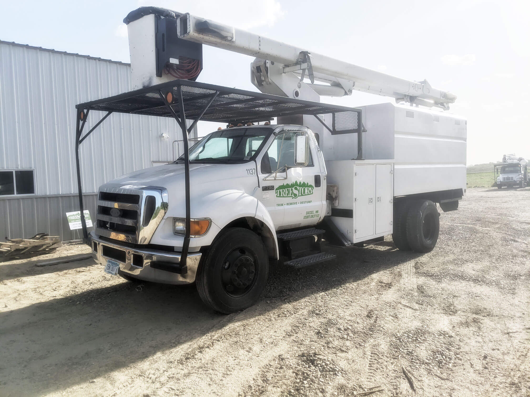 Treemaster truck parked on gravel behind metal shed. This allows TreeStory to cut in tight spaces for commercial tree projects