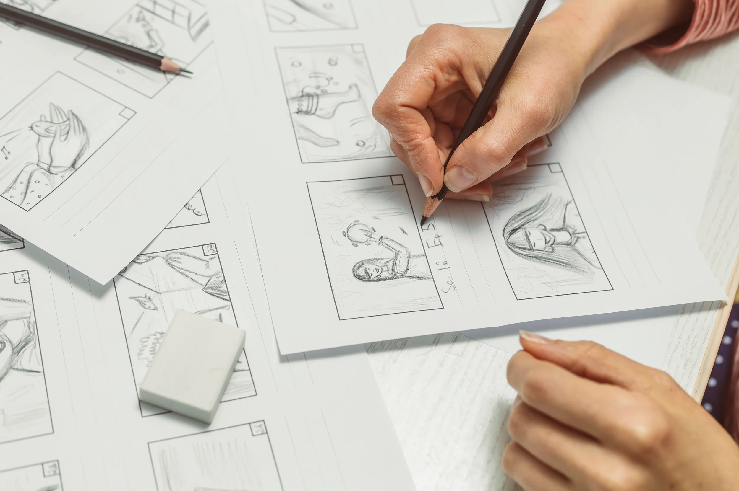 Photo of a hand drawing sketches on paper forming a storyboard.