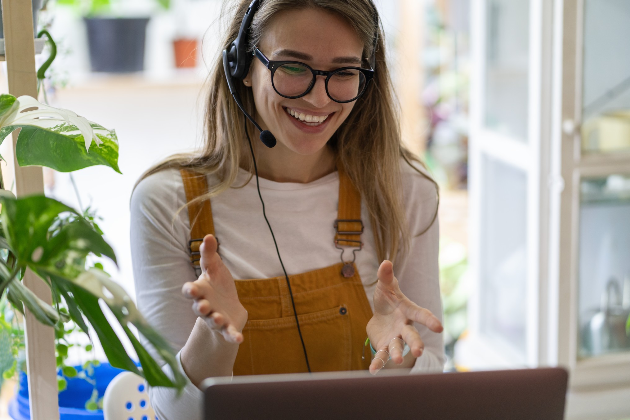 A nonprofit consultant presents to a client via online meeting. She is wearing a headset and smiling at her laptop screen.