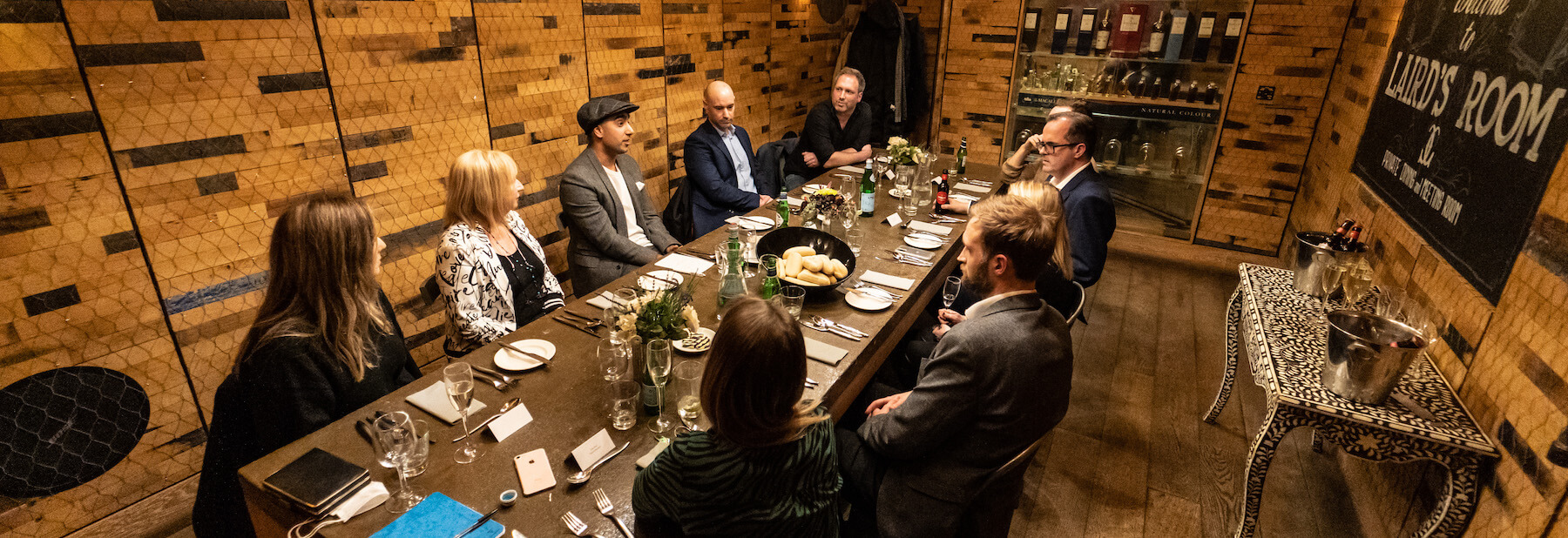 Ten people sitting around a dining table in a room styled to look like a Scottish country house.