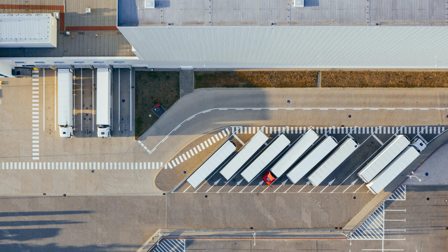 An overhead shot of lorries being loaded with goods at a busy dispatch depot.